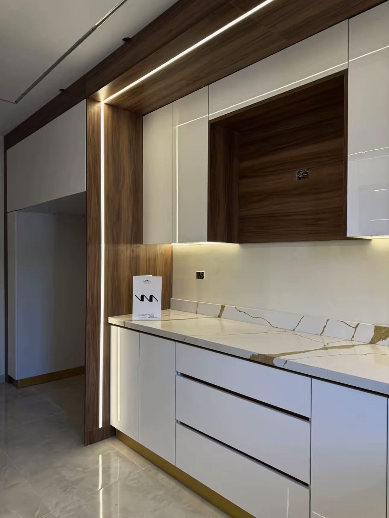 Walnut-framed kitchen wall with LED strip, drawers and marble worktop