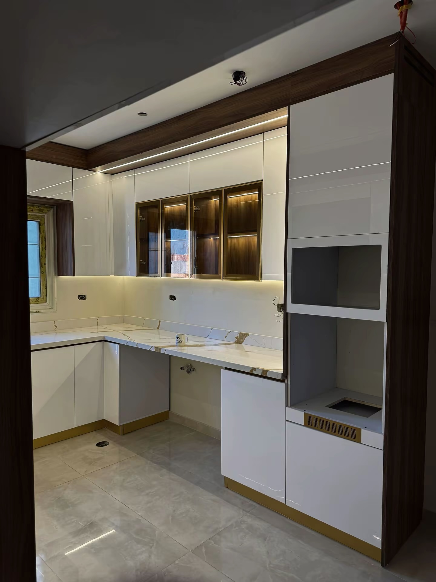 White gloss kitchen with bronze-framed glass cabinets and tall appliance unit